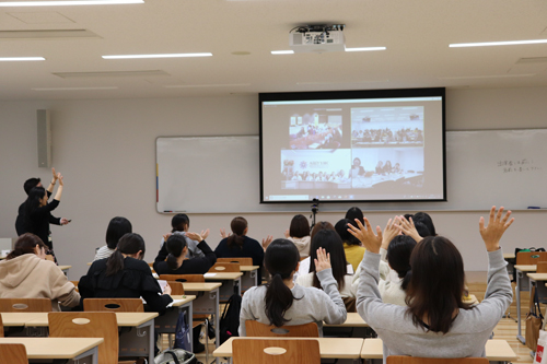 モニターの向こうにいる各大学の学生に手を振る本学の学生ら